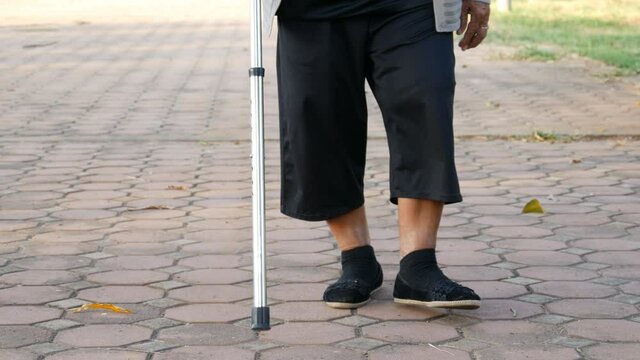 senior woman legs walking with walking stick