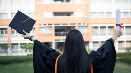 Portrait of happy and excited of young Asian female university graduate wears graduation gown and...