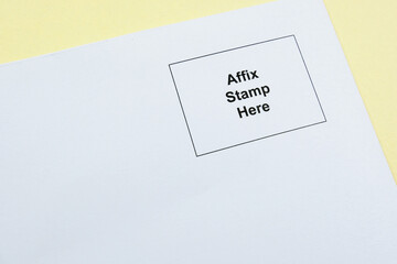 'Affix stamp here' printed on the top right hand corner of a white envelope against a yellow application form requiring the sender to affix postage stamp before posting.