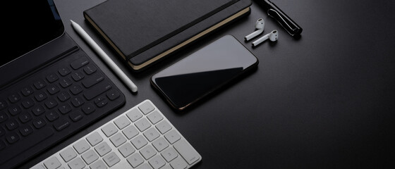 Digital devices with smartphone, tablet, keyboard, stationery, accessories and copy space on dark table - obrazy, fototapety, plakaty