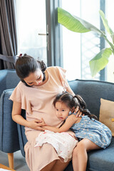 Cute little Vietnamese girl hugging pregnant mother. Pregnancy and new life concept