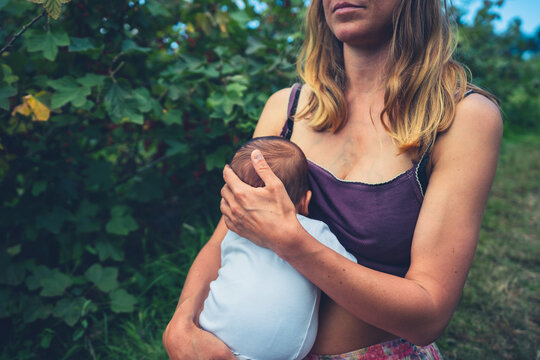 Young woman breastfeeding her baby in nature