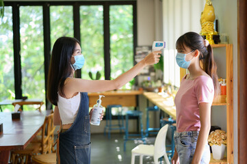 CORONAVIRUS COVID-19 concept, Woman wearing mask with thermoscan or thermometer guns screening for...