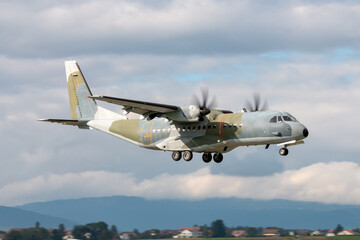 Twin engined camouflaged military cargo airplane on approach to land.