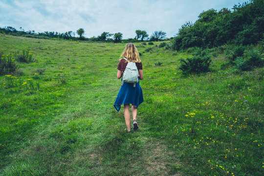 Young woman walking in meadow on summer day