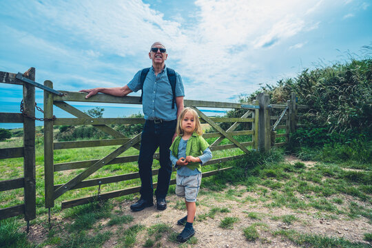 Preschooler and his grandfather by fence in the copuntryside