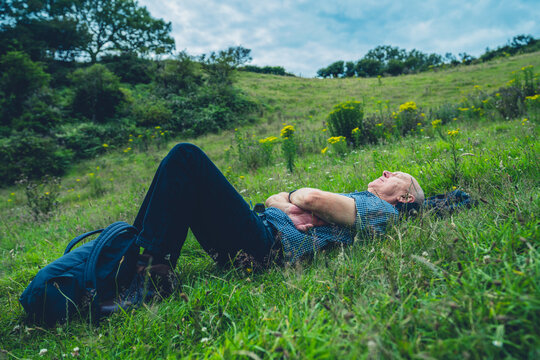 Senior man lying in meadow on a summer day