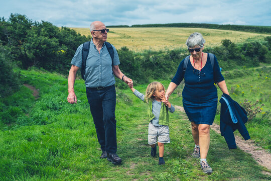 Grandparents walking with preschooler grandchild in the countryside
