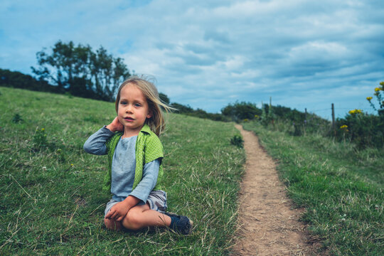 Preschooler boy sitting by path in meadow