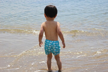 海に向かう幼い子供のうしろ姿