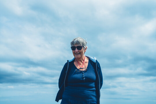 Senior woman standing against cloudy sky