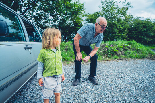 Preschooler with his grandfather by car