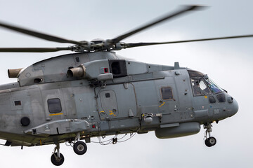 Naklejka na ściany i meble Grey military helicopter flying on an overcast day.