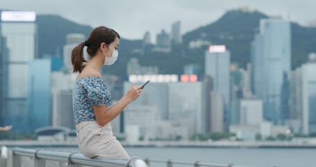 Woman wear face mask and use of mobile phone in Hong Kong