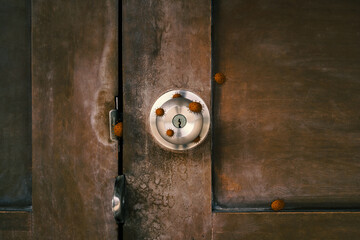 old stainless door knob or handle on grunge wooden door with virus or germ effect, concept of COVID-19 spread and prevention, dramatic tone effect