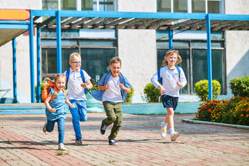 group of school children with backpacks run out of school, after the end of classes.