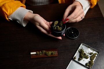 Young woman with cigarrette smoking weed hands nails marijuana grinder  - obrazy, fototapety, plakaty