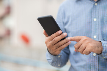 Close up male hands holding using black smartphone on city background.