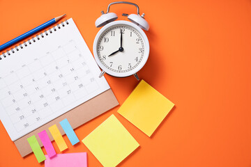 close up of alarm clock and calendar on the orange table background, planning for business meeting...