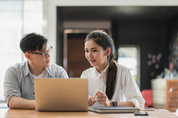 Asian business people man and woman conference talking and working with laptop together. Young couple work at home.