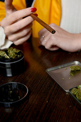 Obraz na płótnie Canvas Young woman with cigarrette smoking weed hands nails marijuana grinder 