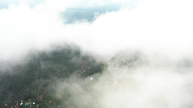 Aerial view of rural village over fast running clouds. Top drone view residential area with houses or cottages. Aerial view of cottage village in the forest	