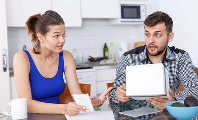 Unhappy young woman and man with box of purchase having conflict at home