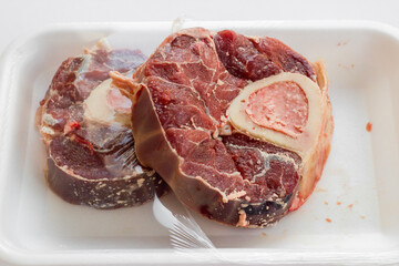 Uncooked two piece of  shank marrow bone of beef on the white packing,top view