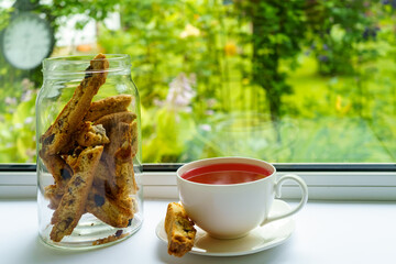 Cup with fruit tea and biscotti cookies on the background of the garden