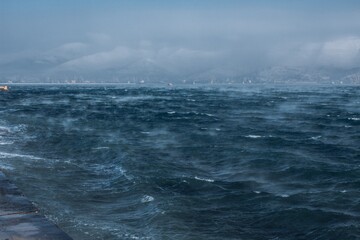fog over the black sea in winter against the background of snow-capped mountains