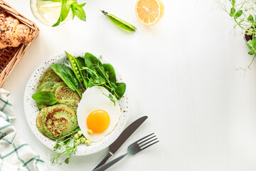 Tasty healthy breakfast. Green pancakes with spinach, egg and young green peas. top view. copy space
