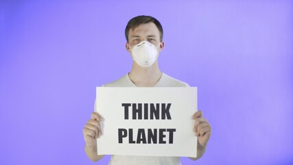 Young Man Activist With mask on face and with Think Planet Poster on Violet background