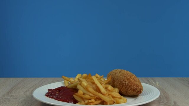 French fries with Kiev cutlet with red sauce appear on a blue background
