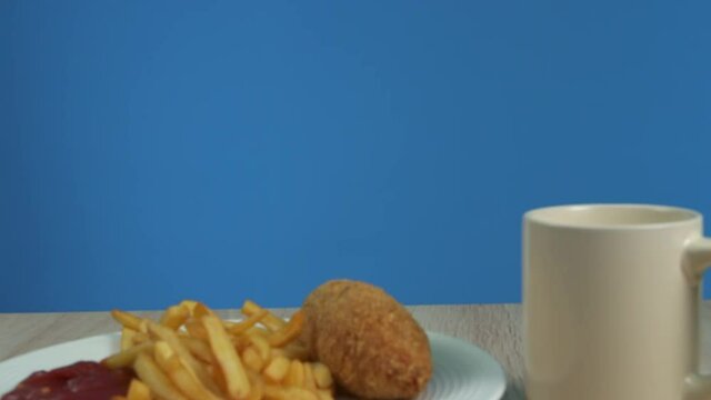 French fries with Kiev cutlet with red sauce appear on a blue background