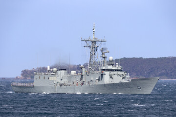 Fototapeta na wymiar Navy warship heading into a harbor.