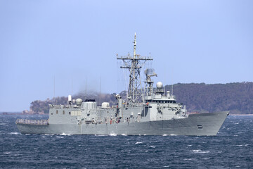 Navy warship heading into a harbor.
