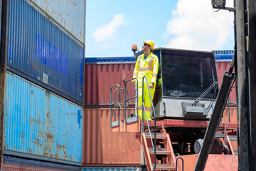 Serious dock worker controlling work processes in the port in container warehouse.