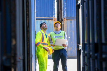 Two foreman workers discussing and checking in shipping yard at container cargo.