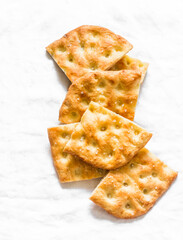 Slices of crispy thin Italian focaccia on a light background, top view