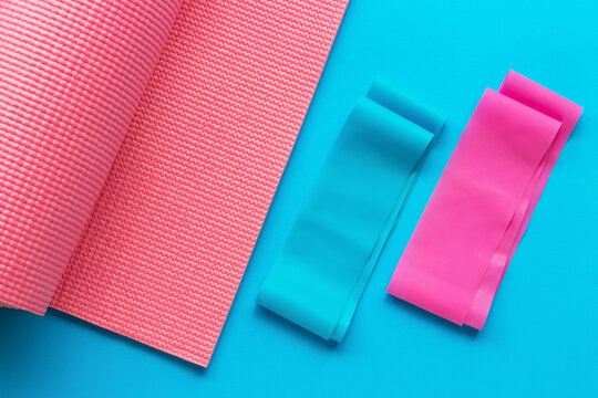 Gymnastic mat and sports gum espander on blue background, view from above