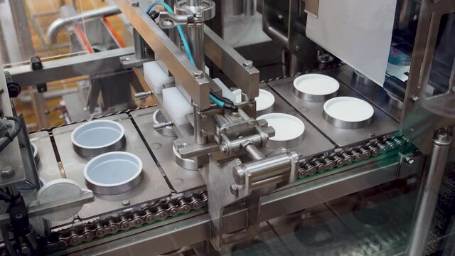 Filling plastic cups with sour cream on a conveer.