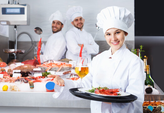 Portrait of confident woman chef standing with serving tray in fish restaurant
