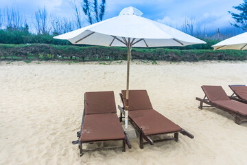 White sand beach with chaise chairs and white umbrella in clear blue sky with many tourists at Muine Bay Resort, Mui Ne, Phan Thiet city, Binh Thuan province, Vietnam