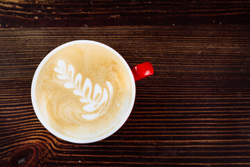 Fresh brewed coffee with latte art in red cup. Close up. Flat lay
