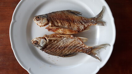 Fried fish on a white plate, top view