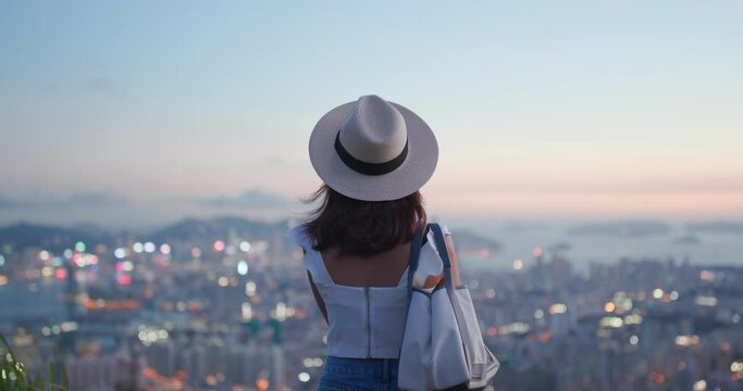 Woman tourist with straw hat and look at the city view at sunset time