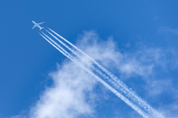Large four engined commercial airliner jet aircraft flying at high altitude with a large contrail...