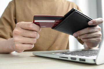 The businessman's hand is holding a credit card and using a laptop for online shopping and internet payment in the office