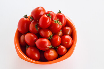 Ripe,delicious cherry tomatoes heap in red bowl,on white with copy space