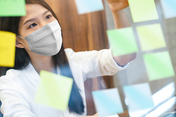 attractive asian female white shirt working while wearing protective virus mask working in co...